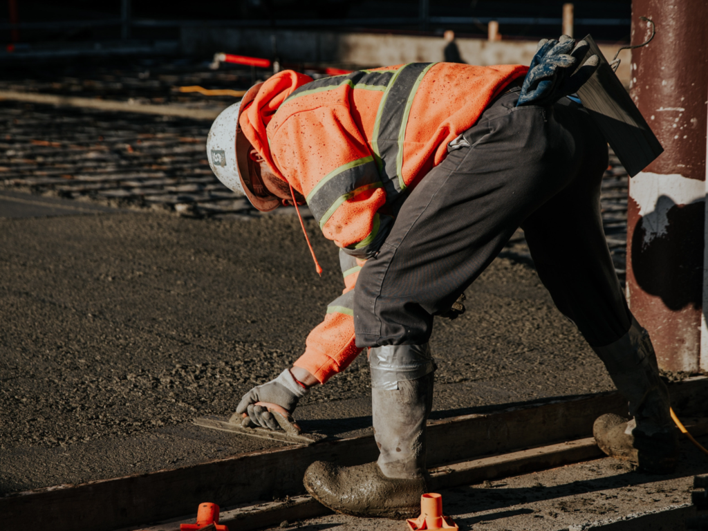 Worker from JKT Outdoor Services Ltd. levelling gravel pad during installation in Parkland County, Alberta, Canada.